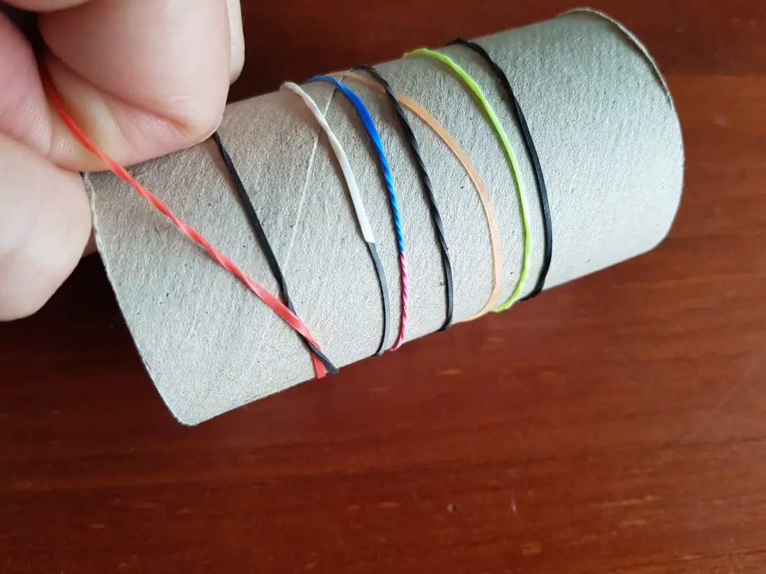 Ensartar gomas de colores en un tubo de cartón